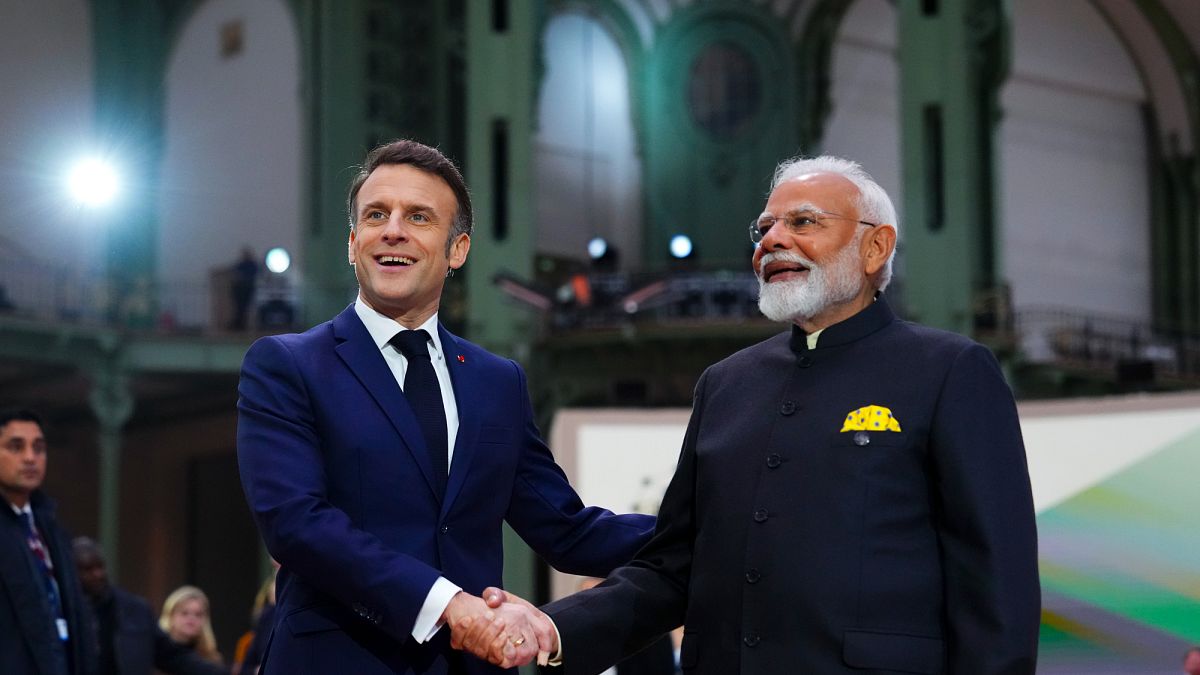 French President Emmanuel Macron shakes hands with India