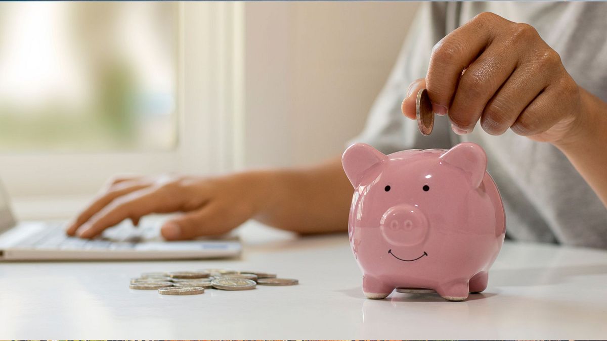 A woman putting a coin into a piggy bank