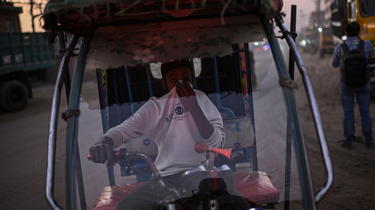 An autorickshaw driver covers his face to protect himself from the pollution in Dhaka, Bangladesh.