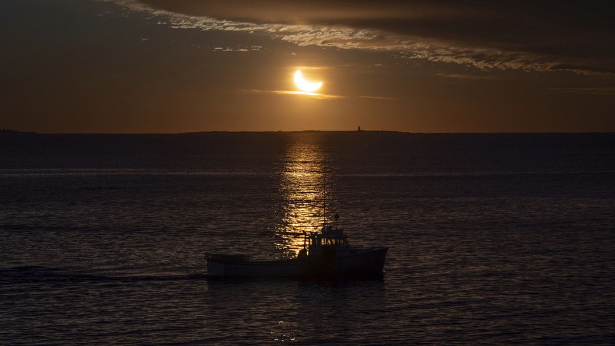 A fishing boat is silhouetted during a partial solar eclipse in Halifax on Saturday, March 29, 2025.