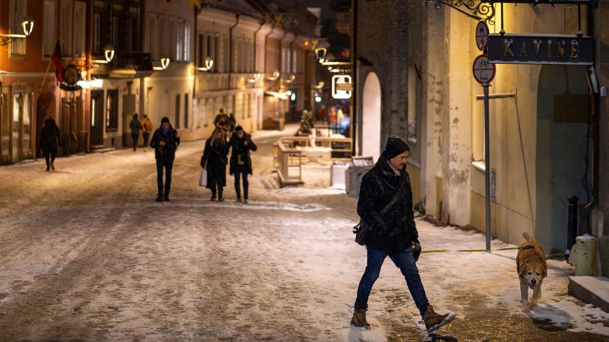 A person with a dog walks through the snow-covered Old Town in Vilnius, Lithuania, 17 February 2025.