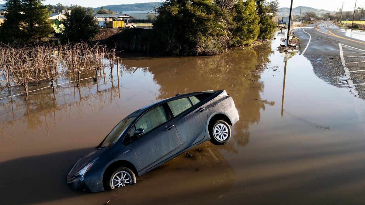 A vehicle is partially submerged in floodwater along State Route 121 following an atmospheric river event near Schellville in California.