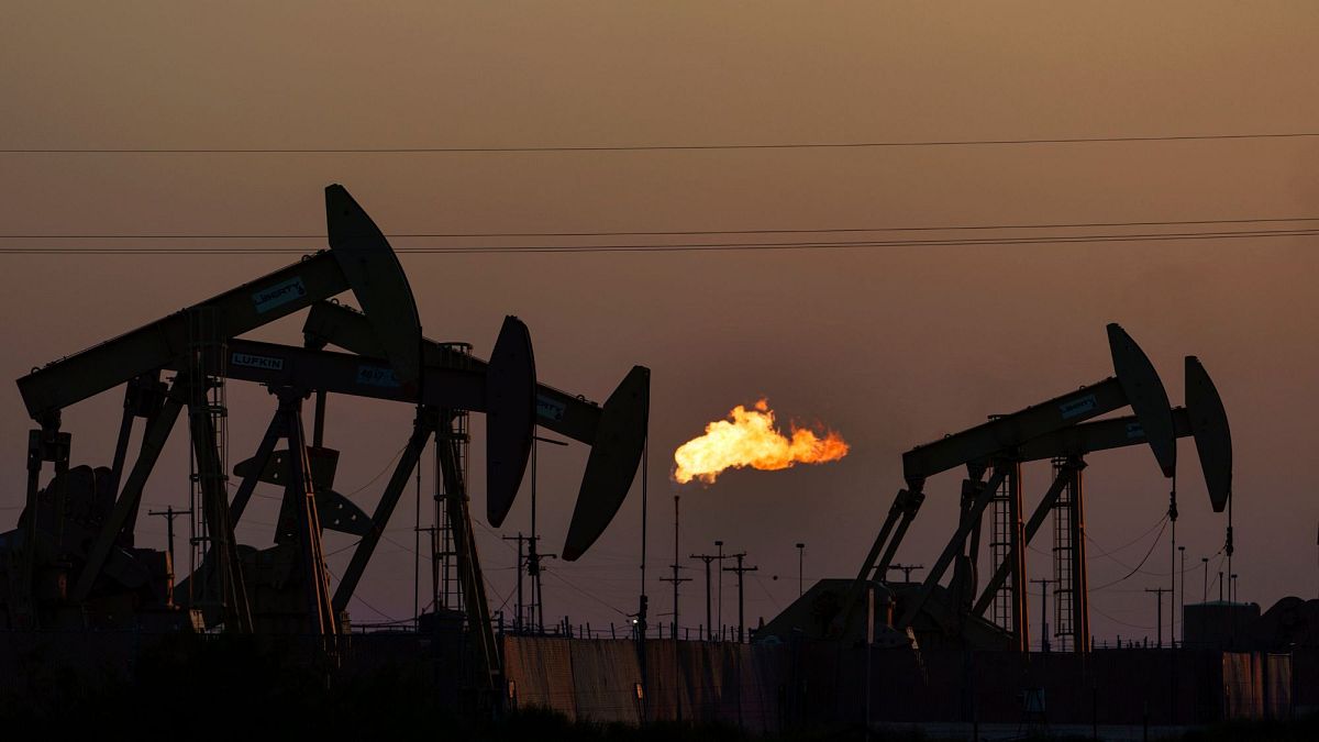 A flare burns off methane and other hydrocarbons as oil pumpjacks operate in the Permian Basin in Midland, Texas, 2021.