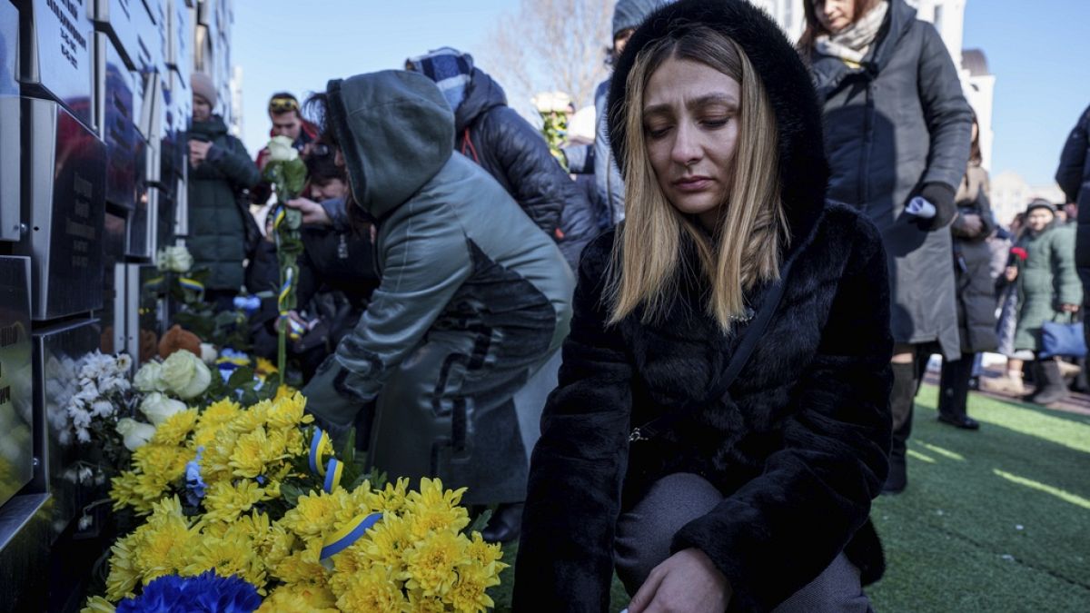 People put flowers at a memorial for killed civilians during a ceremony to mark the third anniversary of the Russian invasion of Ukraine, in Bucha, Ukraine, Feb. 24, 2025