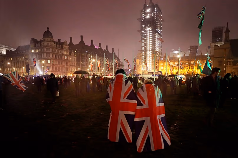 DATEI – In britische Flaggen gehüllte Menschen laufen während der Regenfälle in London am 31. Januar 2020 über den Parliament Square