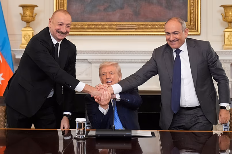 Der Präsident von Aserbaidschan, Ilham Aliyev, und der Premierminister von Armenien, Nikol Pashinyan, geben sich die Hand, während US-Präsident Donald Trump zwischen ihnen sitzt, 8. August 2025
